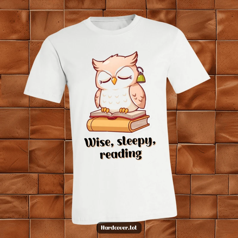Funny sleepy owl character perched on a book, wearing a small reading lamp, printed on a soft t-shirt.